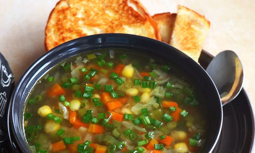 Warm clear vegetable soup in a round bowl